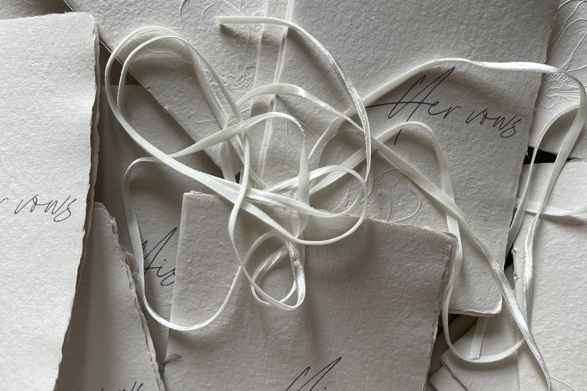 Handmade paper wedding vow cards with deckled edges and silk ribbon, an example of relaxed informal wedding stationery