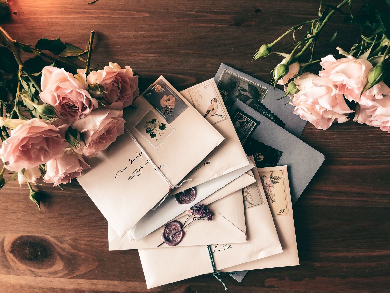 Stack of addressed wedding envelopes with vintage stamps and wax seals, one per household