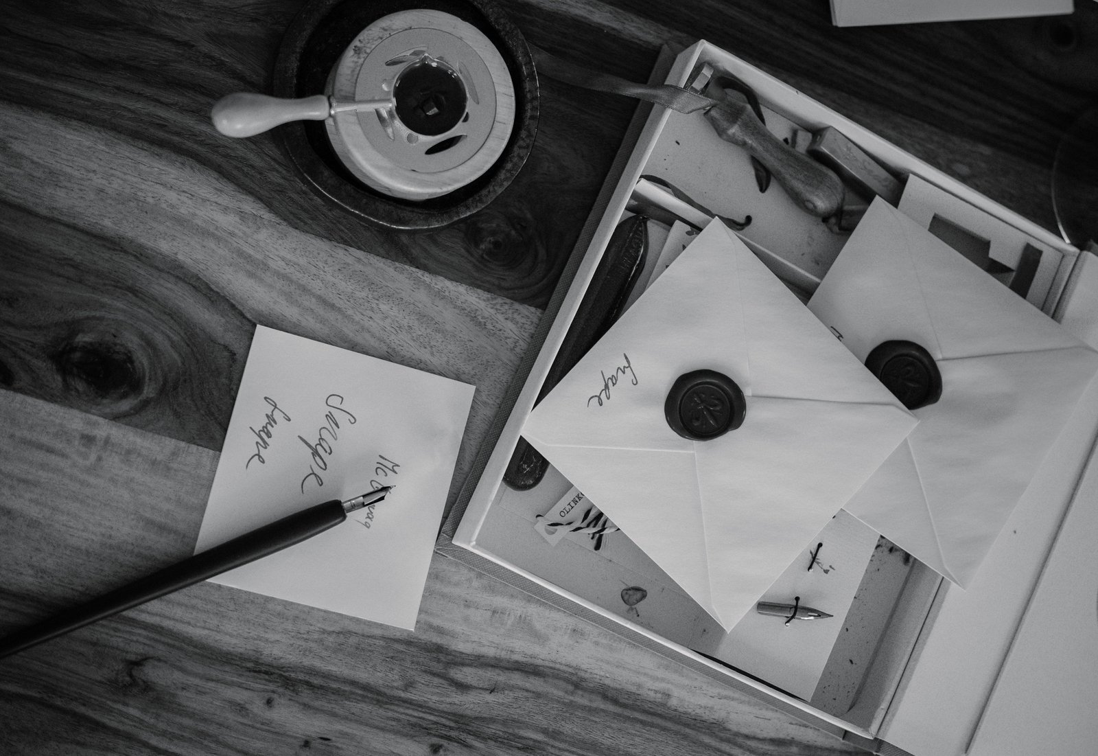 Calligraphy pen and ink beside hand-addressed wedding envelopes on a wooden desk